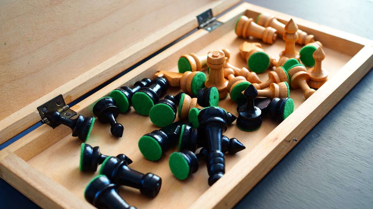 Close-up view of wooden and plastic chess pieces inside an open wooden box, with a focus on detail and color.